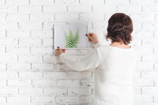 Foto detrás de la mujer que cuelga su bosquejo en la pared.