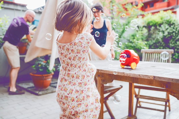 Por detrás de la niña jugando con jabón de burbujas