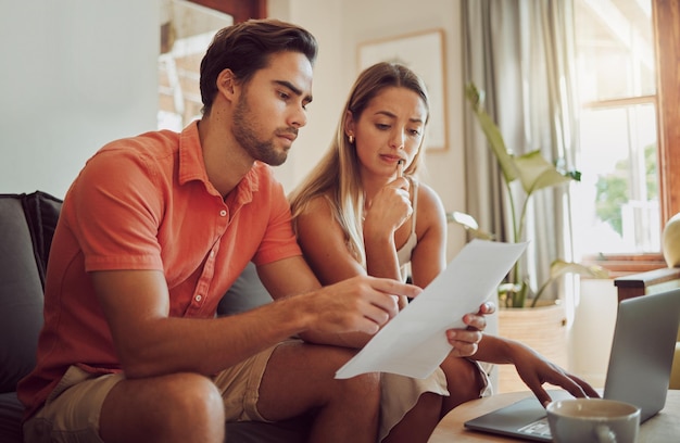 Deuda de ansiedad y estrés con una pareja pagando facturas en una computadora portátil revisando su presupuesto y ahorros El esposo y la esposa jóvenes parecen preocupados mientras leen juntos una solicitud de préstamo o un contrato