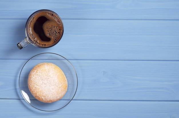 Deutscher Donut-Berliner mit Puderzucker und Tasse Kaffee auf blauem Holztisch, Draufsicht mit Kopierraum