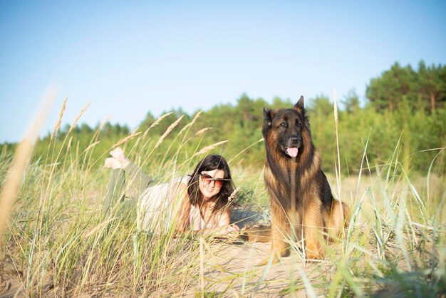 Deutscher Schäferhund und Frau auf Strandhintergrund