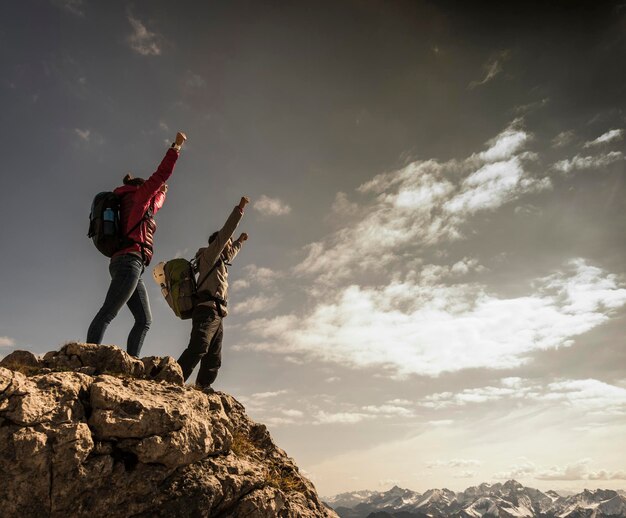 Deutschland, Bayern, Oberstdorf, zwei Wanderer jubeln auf einem Felsen in alpiner Landschaft