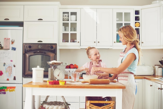 Devemos assar com mais frequência mãe Menina bonitinha assando na cozinha com a mãe