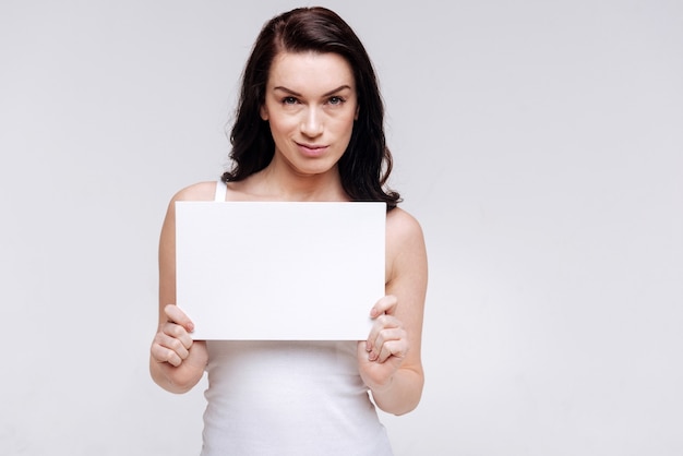 Devota mujer elegante posando con un trozo de papel en blanco, igualdad social