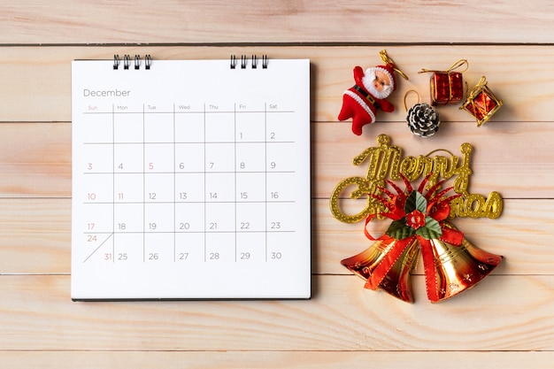 Foto dezember kalender und weihnachtsdekoration - weihnachtsmann und geschenk auf holztisch. weihnachts- und frohes neues jahr-konzept