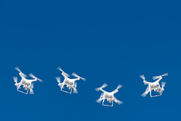 Dezenas de drones enxameiam no céu azul. Quadcopters drones com câmera digital no ar sobre a cidade.