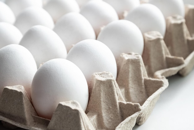 Dezenas de ovos de galinha brancos frescos na bandeja de papel