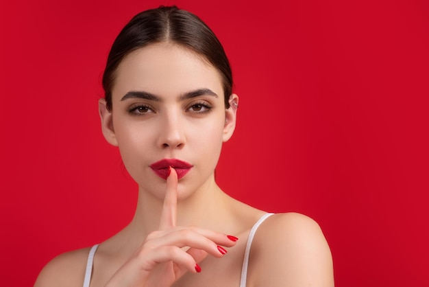 Foto di silencio secreto cállate con el dedo en los labios gesto shhh aislado en el retrato de fondo del estudio