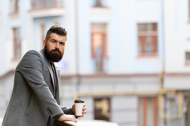 El día acaba de comenzar Empresario en estilo hipster sosteniendo café para llevar Hipster con vaso de papel caminando en la ciudad Hombre barbudo disfrutando del café de la mañana Bebiendo su taza a primera hora de la mañana