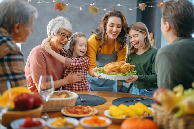 Día de Acción de Gracias, fiesta de otoño. Familia feliz sentado a la mesa y celebrando las vacaciones. Abuelos, madre, padre e hijos. Cena tradicional.