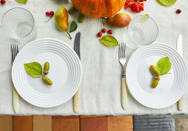 El día de acción de gracias o el ajuste de lugar de la mesa de la cena de Halloween decorativo con calabaza, bellotas, hojas de peras sobre fondo de mantel blanco, vista desde arriba, vista superior, endecha plana