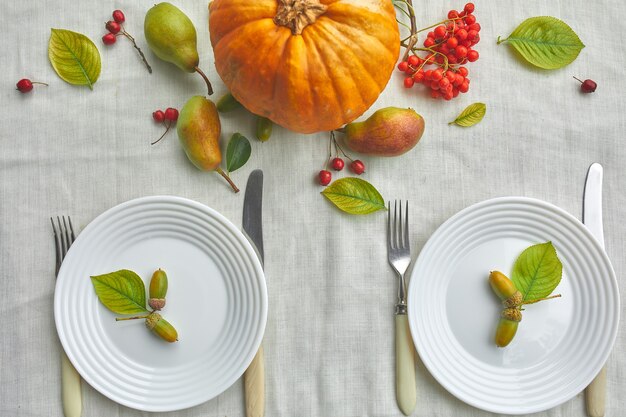 El día de acción de gracias o el ajuste de lugar de la mesa de la cena de Halloween decorativo con calabaza, bellotas, hojas de peras sobre fondo de mantel blanco, vista desde arriba, vista superior, endecha plana.