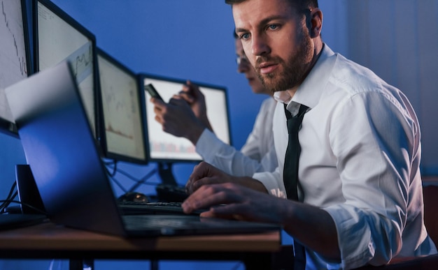 Foto día ajetreado dos comerciantes de acciones que trabajan en la oficina con tecnología de intercambio