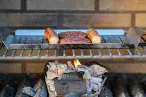 Foto día de barbacoa en casa hamburguesas y perritos calientes alemanes a la parrilla en el fuego concepto de fiesta de familia y amigos