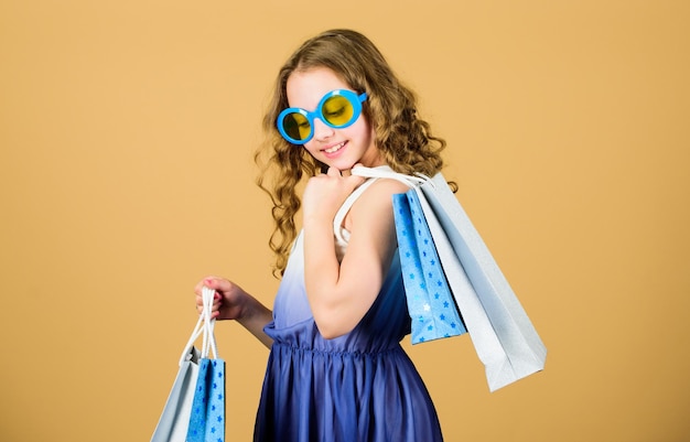 Día de compras Chica de moda infantil Gafas de sol con paquete Marca de niños favorita Chica con bolsa de compras Tour de compras en el extranjero Venta de temporada de verano Compras y compras Black friday Descuento de venta