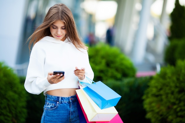 Dia de compras. Mujer sosteniendo bolsas de colores cerca de su centro comercial shooping en viernes negro de vacaciones.