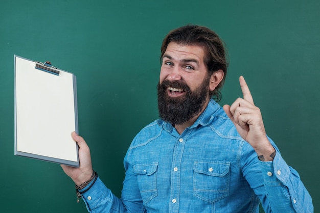 Día del conocimiento de la idea maestro barbudo maduro con carpeta de documentos trabajo de hombre brutal en el aula con pizarra prepararse para el examen profesor universitario en la lección de regreso a la escuela educación formal