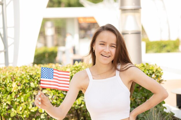 Dia da Independência eua festeira adolescente com bandeira americana em dia de verão sorrindo comemorando regozijo