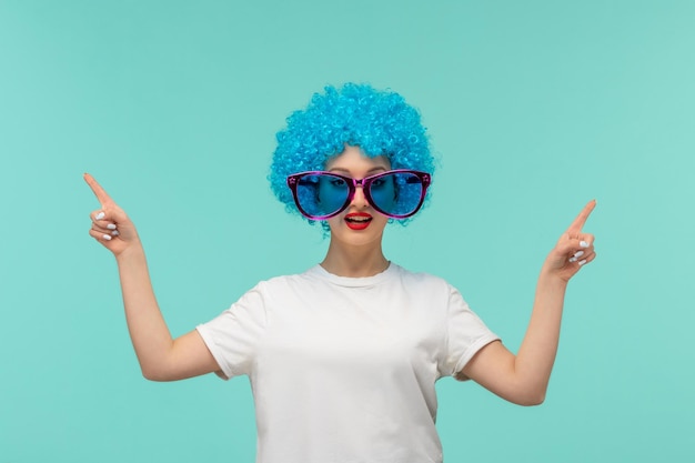 Dia da mentira palhaço dedos apontando para cima grandes óculos de sol azuis traje engraçado cabelo azul