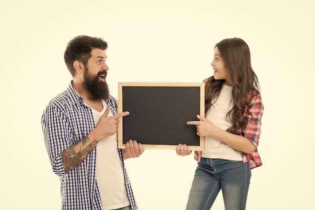 Dia das crianças Família feliz Homem barbudo pai com filha Menina ama seu pai Felicidade infantil Menina apontando no quadro-negro Pai e filha seguram espaço de cópia de quadro vazio