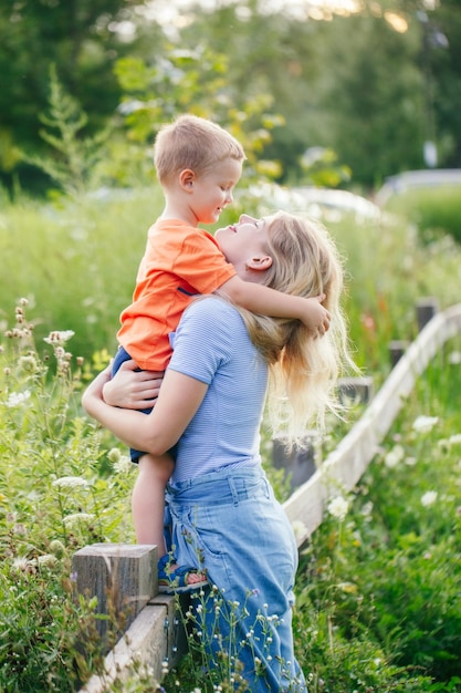 Dia das Mães feriado jovem mãe caucasiana e menino filho bebê abraçando abraçando no parque ao ar livre