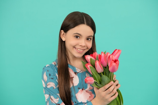 dia das mães ou das mulheres. garoto segura flores para 8 de março. menina adolescente segura buquê de primavera sobre fundo azul. presente floral. criança feliz com tulipas.