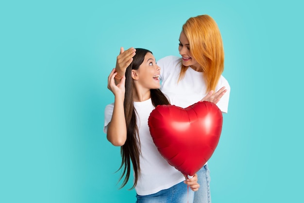 Dia das mães Sorrindo mãe e filha segurando balão de coração de amor no fundo azul Mamãe