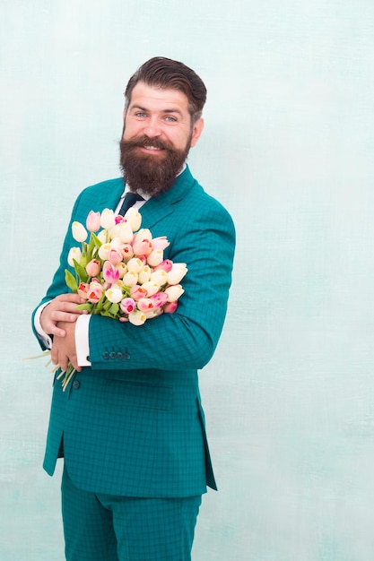 Dia das mulheres 8 de março Presente de primavera Homem barbudo hipster com flores Comemore a primavera Fazendo surpresa Cavalheiro com tulipas A primavera está chegando Saudações Homem barbudo com buquê de tulipas Data de amor