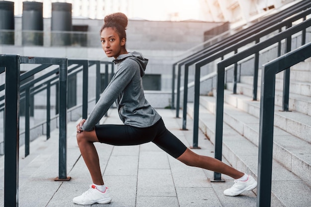 Dia de alongamento Jovem afro-americana em roupas esportivas tem treino ao ar livre