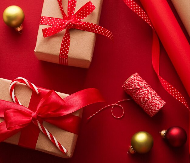 Dia de boxe de preparação de natal e presentes de feriados dando papel artesanal de natal e fitas para caixas de presentes em fundo vermelho como ferramentas de embrulho e decorações diy presentes como apartamento de férias