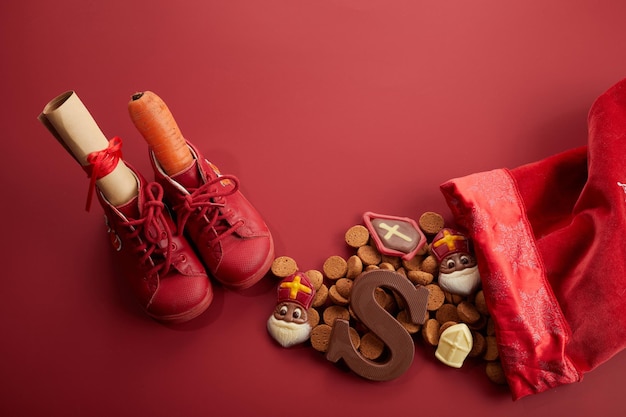 Dia de São Nicolau Sinterklaas com cenoura de sapato e doces tradicionais em fundo vermelho