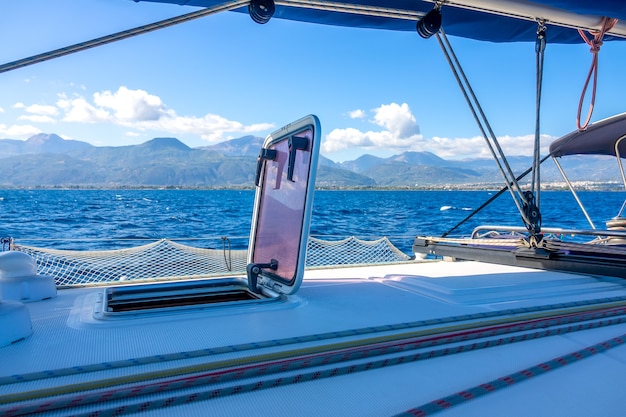 Dia de sol de verão a bordo de um iate à vela. rigging e mastro. vista da costa montanhosa