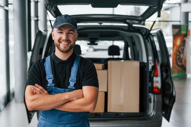 Dia de trabalho O entregador de uniforme está dentro de casa com carro e com pedido