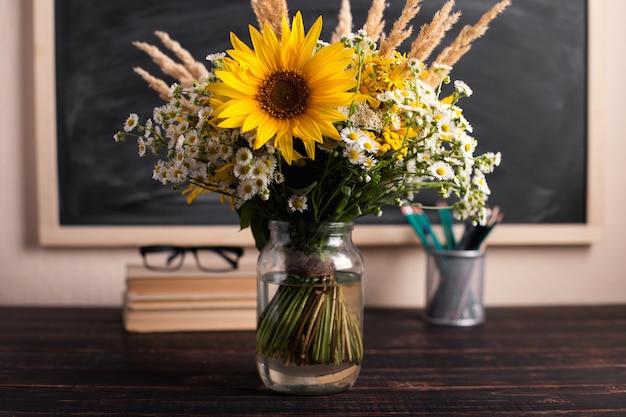 Dia do professor. placa de giz preto e flores silvestres frescas em vaso