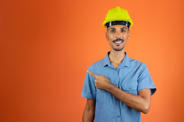 Dia dos engenheiros homem negro em capacete de segurança e camisa azul isolado em laranja