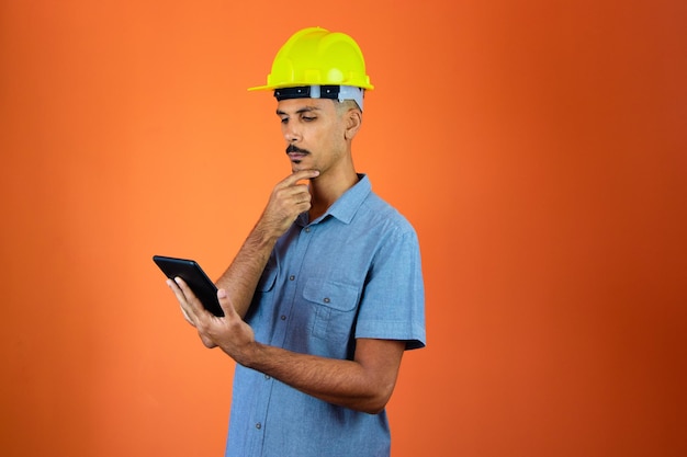 Dia dos engenheiros Homem negro em capacete de segurança e camisa azul isolado Engenheiro segurando celular