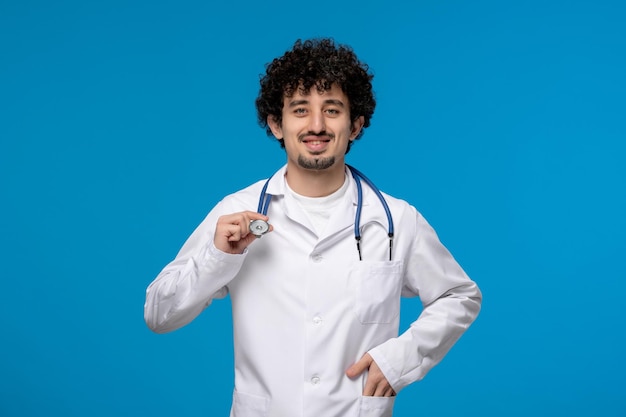 Dia dos médicos cara bonito e bonito em uniforme médico segurando um estetoscópio