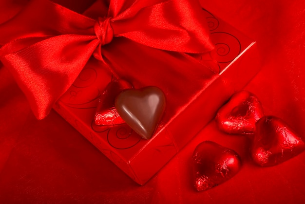 Dia dos Namorados. Caixa de presente e bombons em forma de coração em fundo vermelho