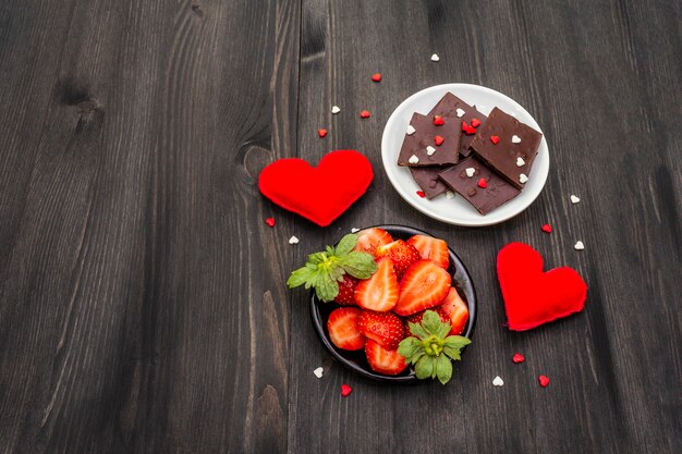 Dia dos namorados conceito romântico. Chocolate, morango maduro fresco, corações de feltro vermelhos. Sobremesa doce para os amantes.