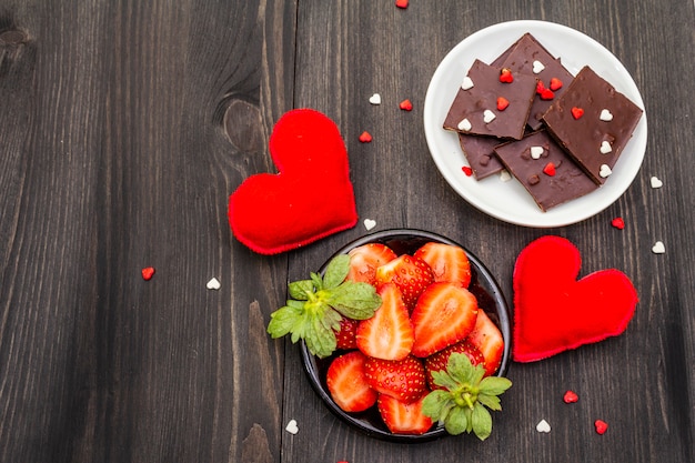 Foto dia dos namorados conceito romântico. chocolate, morango maduro fresco, corações de feltro vermelhos. sobremesa doce para os amantes.