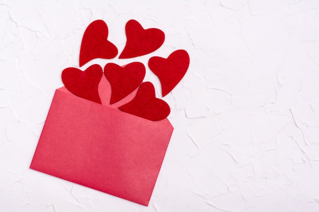 Foto dia dos namorados. corações de feltro vermelho voam para fora de um envelope vermelho aberto. copie o espaço