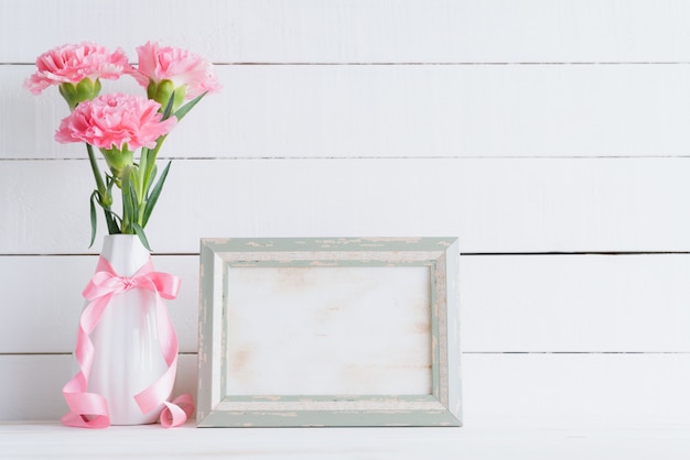 Dia dos namorados e conceito de amor. cravo cor-de-rosa no vaso no fundo de madeira.