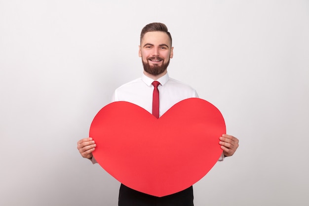 Dia dos namorados empresário de energia sorridente segurando um grande coração vermelho