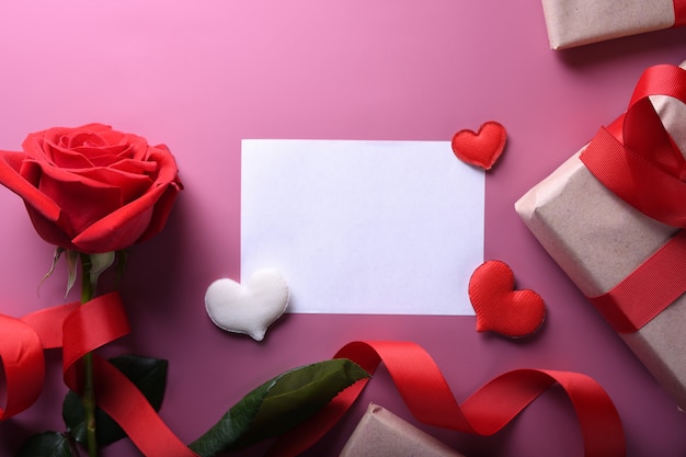 Dia dos namorados fundo cartão amor símbolos, decoração vermelha com óculos coração rosas presentes em fundo rosa. Vista superior com cópia espaço e texto.