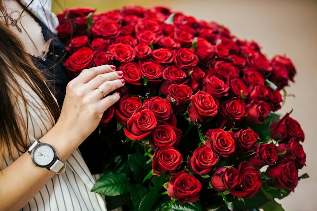 Dia dos namorados. Mulher segurando o buquê de rosas vermelhas. Menina bonita recebeu presente romântico.