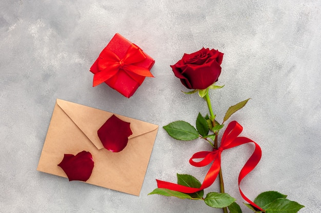 Dia dos namorados. Rosa vermelha com uma fita, carta de amor e caixa vermelha.