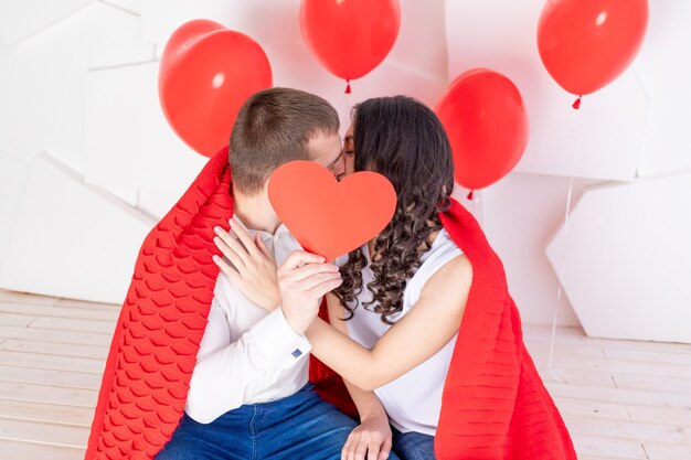 Dia dos namorados, um casal apaixonado se beijando atrás de um coração vermelho