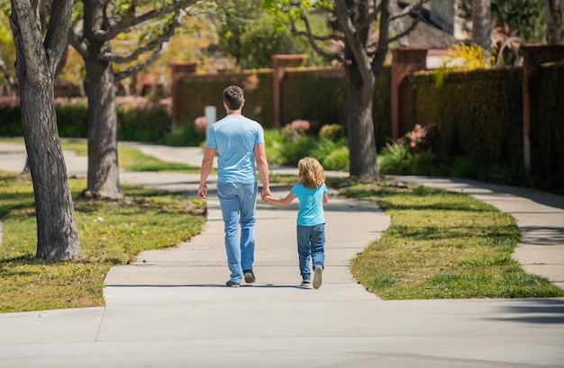 Dia dos pais, pai e filho caminham no parque, vista traseira, valor familiar, infância e paternidade