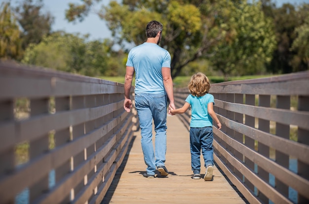 Dia dos pais pai e filho caminhando ao ar livre vista traseira valor familiar infância e paternidade