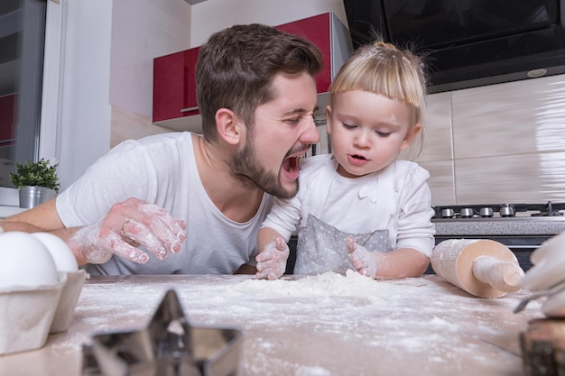 Dia dos pais uma pequena menina doce com cabelo loiro passa o tempo com o pai cozinhando na cozinha